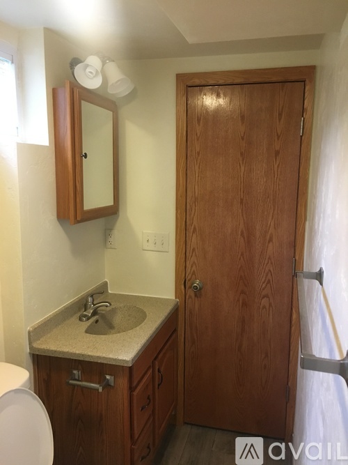 A bathroom with a sink, toilet, and wooden door.