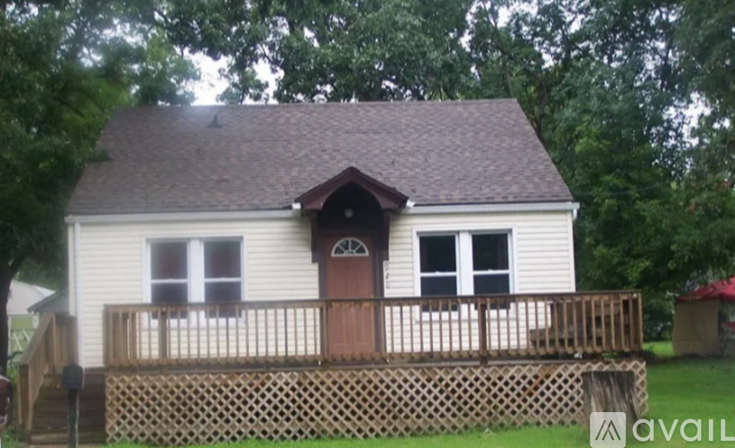 A small white house with a brown door and a brown fence.