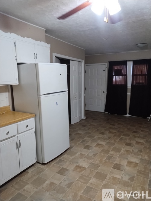 A kitchen with white cabinets and a white refrigerator.