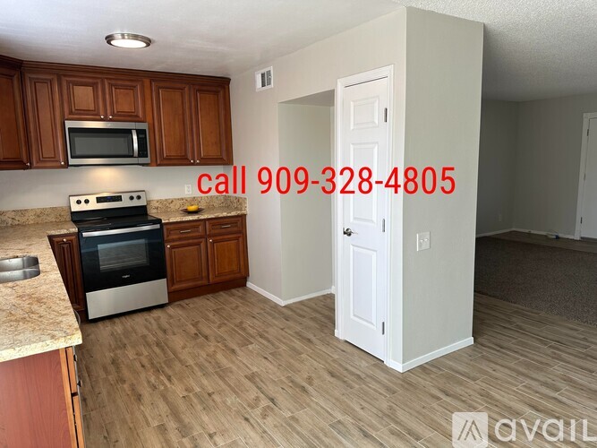 A kitchen with a stove top oven and microwave, a door and a phone number on the wall.