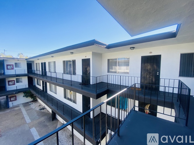 A balcony of a building with a black railing and a small tree.