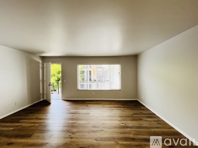 A room with wooden floors and white walls, with a doorway leading to another room.