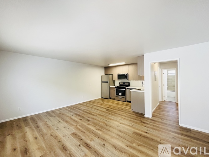 A kitchen area with wooden flooring and white walls.