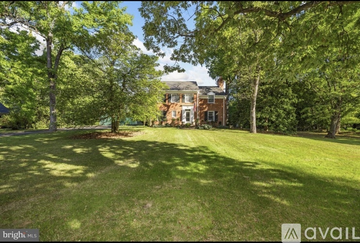 A large grassy area with trees and a house in the background.