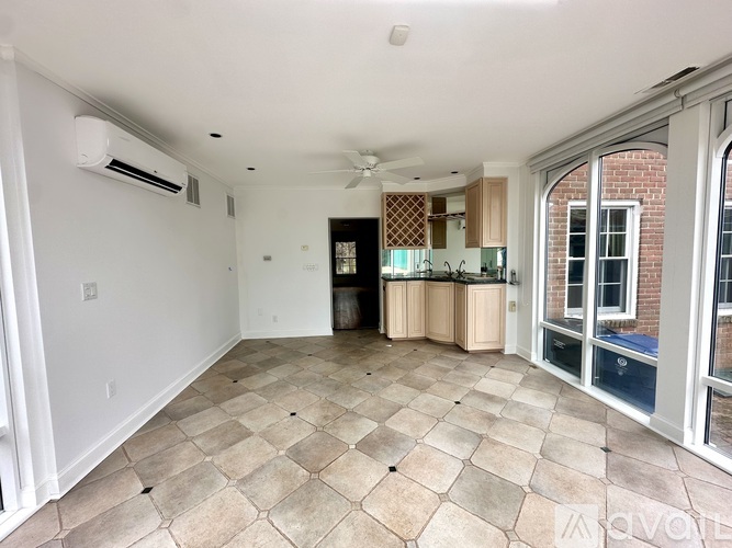 A spacious living room with a checkered tile floor and a ceiling fan.