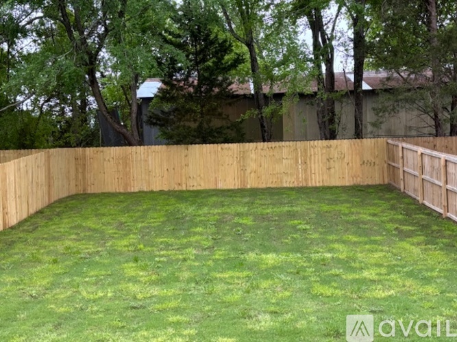 A backyard with a wooden fence and green grass.
