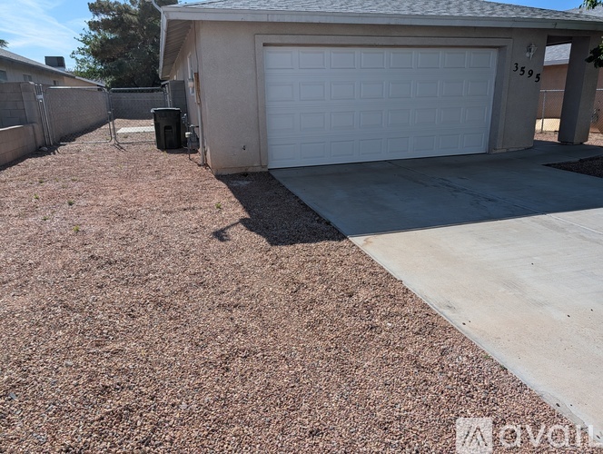A garage with a white door and a brown gravel driveway.