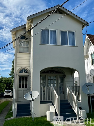 A two-story house with a white exterior and a blue staircase.