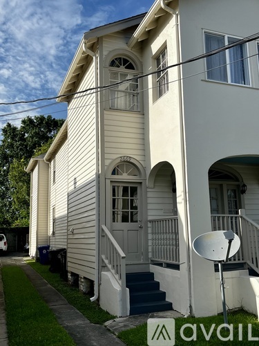 A white house with a satellite dish on the front porch.