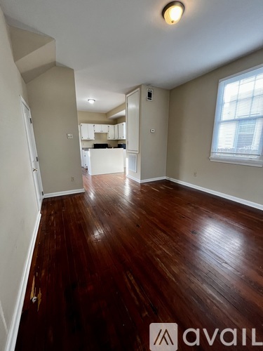 A room with wooden floors and a window on the right side.
