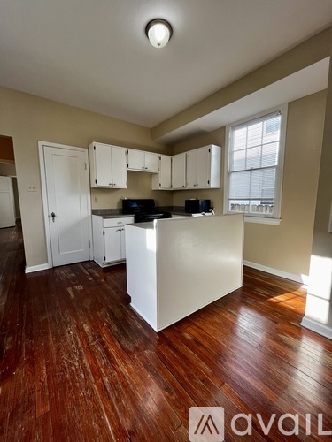 A kitchen with wooden floors and white cabinets.