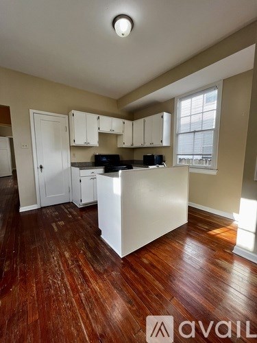 A kitchen with wooden floors and white cabinets.