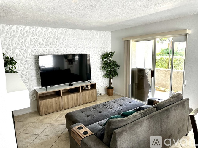 A grey couch sits in a living room with a television and wooden cabinet.