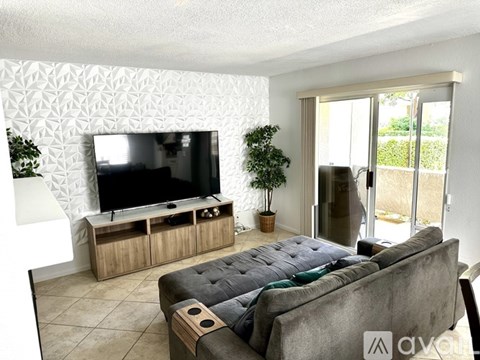 A grey couch sits in a living room with a television and wooden cabinet.