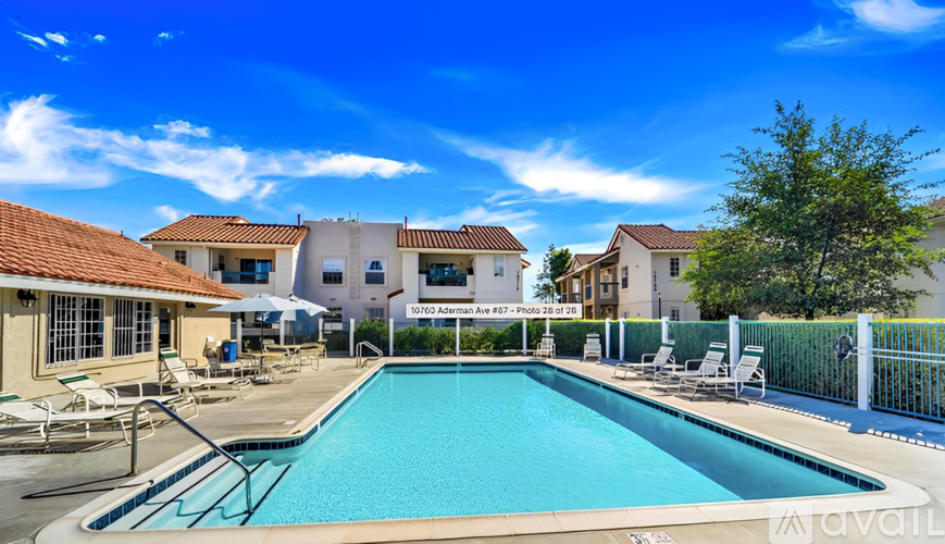 A pool surrounded by chairs and buildings with a sign that says "Levada Apartments.".