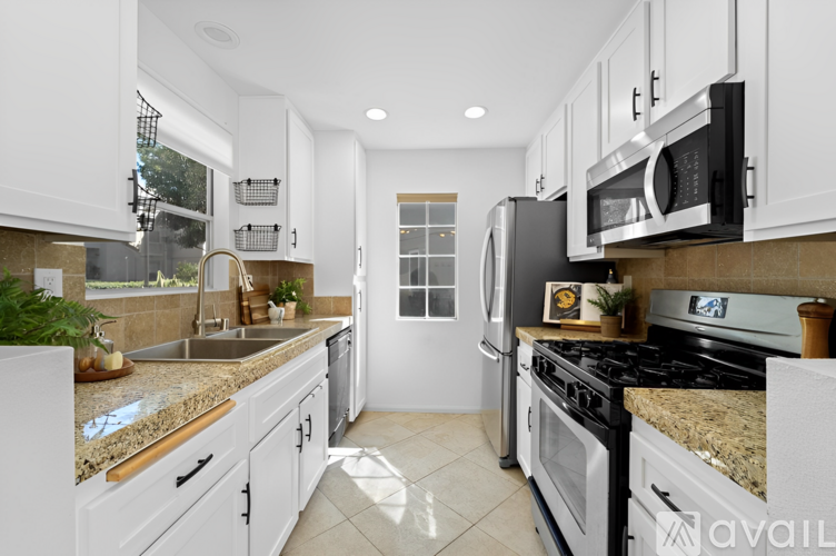 A kitchen with white cabinets and granite countertops.