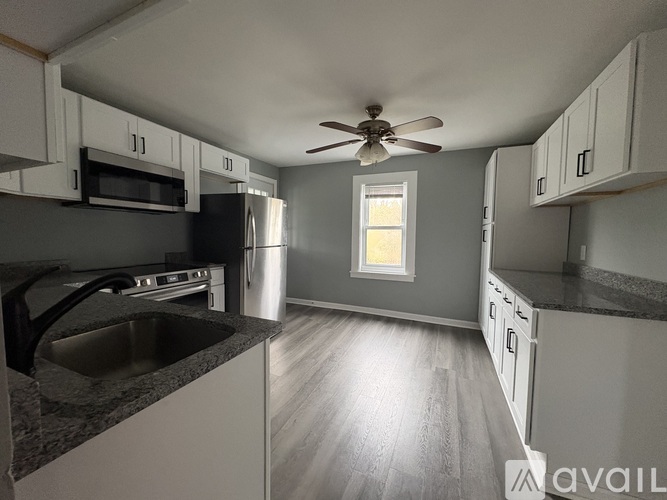 A kitchen with a fan on the ceiling and a window letting in light.