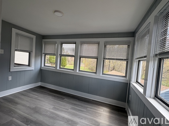 A room with grey walls and wooden flooring with four windows.