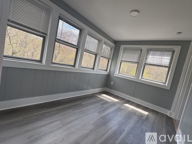 A room with grey walls and wooden flooring with three windows.