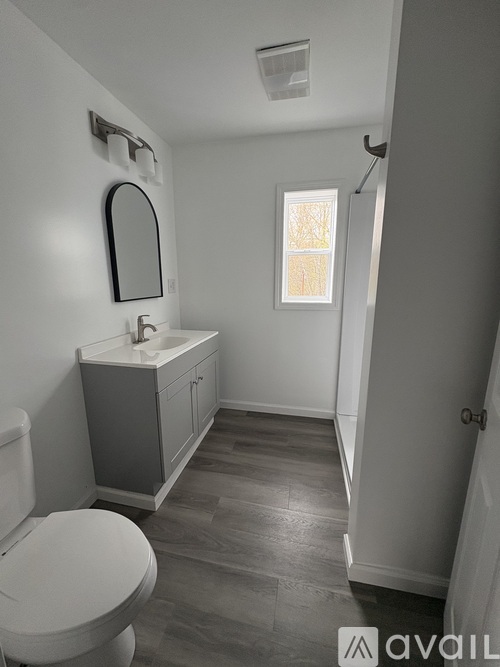 A bathroom with a toilet, sink, and mirror.