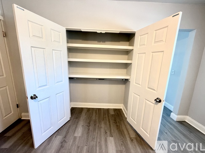 A white closet with shelves and two doors.