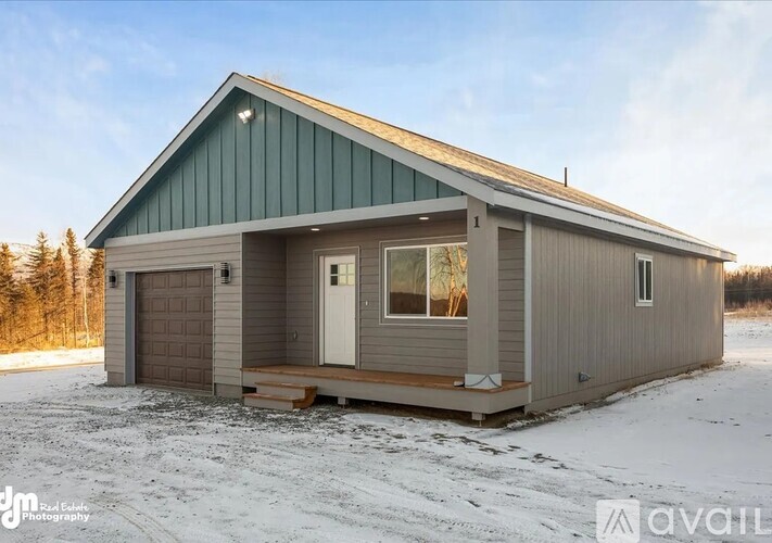 A small house with a garage is situated in a snowy landscape.