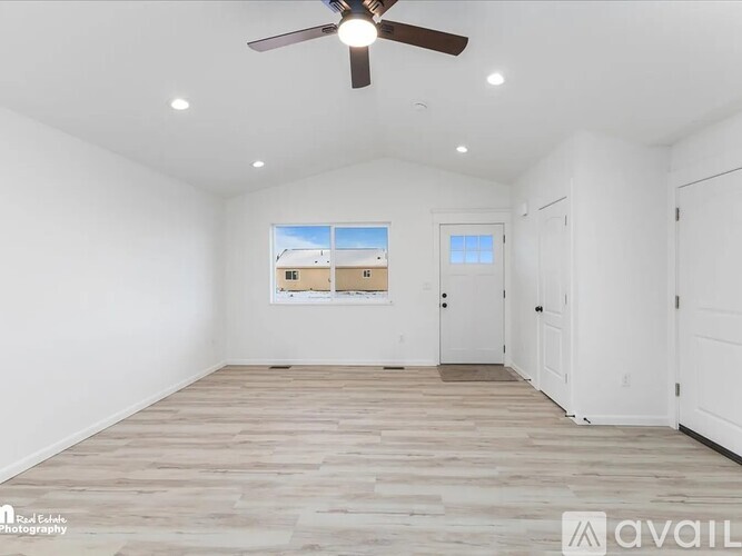 A spacious room with a ceiling fan and a view of a building outside the window.