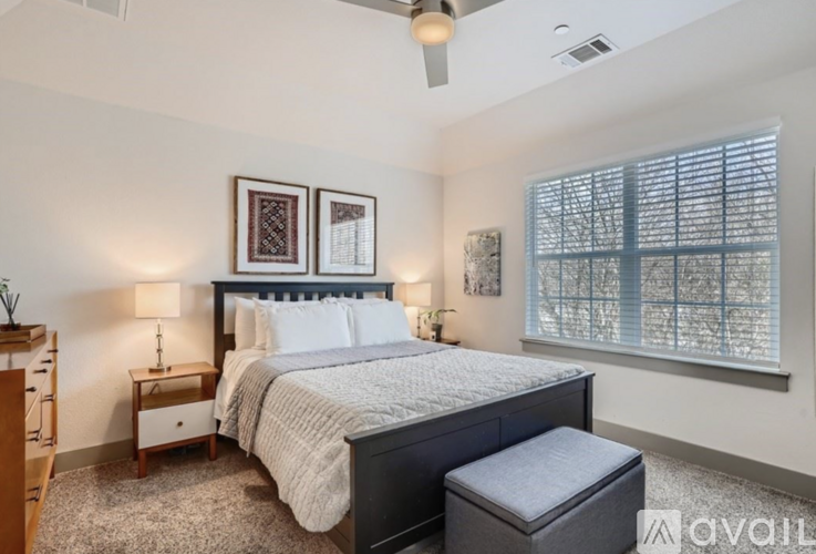 A bedroom with a large bed, a window with blinds, and a ceiling fan.