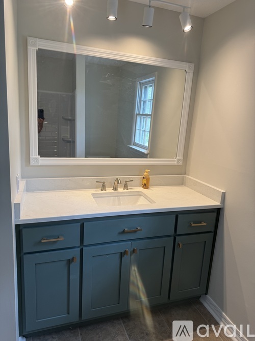 A bathroom with a white countertop and blue cabinets.