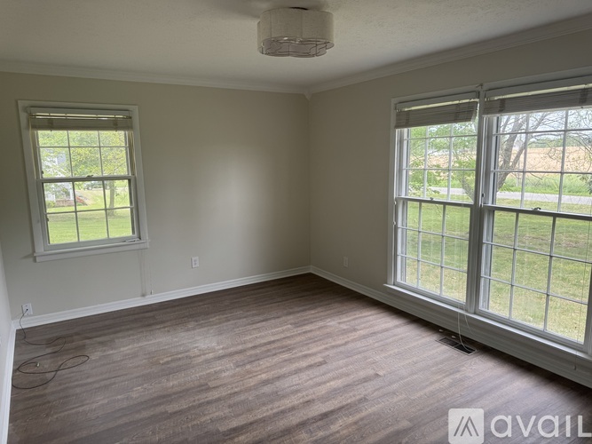 A room with a window and a wooden floor.