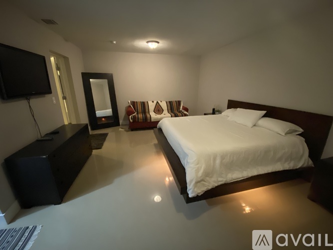 A bedroom with a large bed and a flat screen TV mounted on the wall.