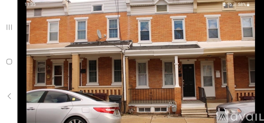 A silver car is parked in front of a brick house.
