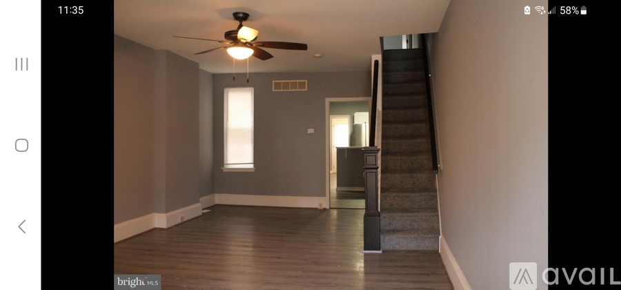 A spacious room with a staircase and a ceiling fan.