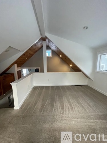 A spacious attic room with a carpeted floor and a window.
