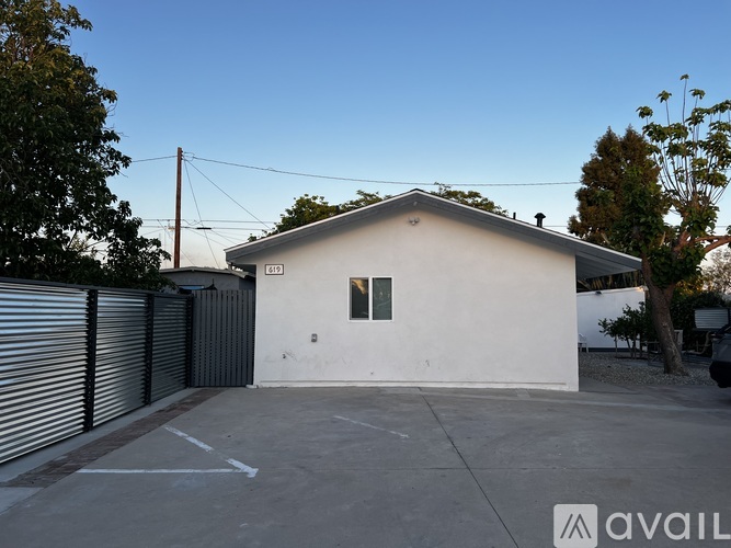 A small white building with a garage door is situated in a parking lot.