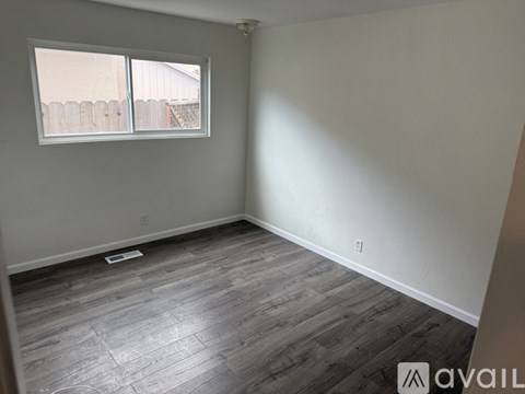 A room with a window and wooden flooring.