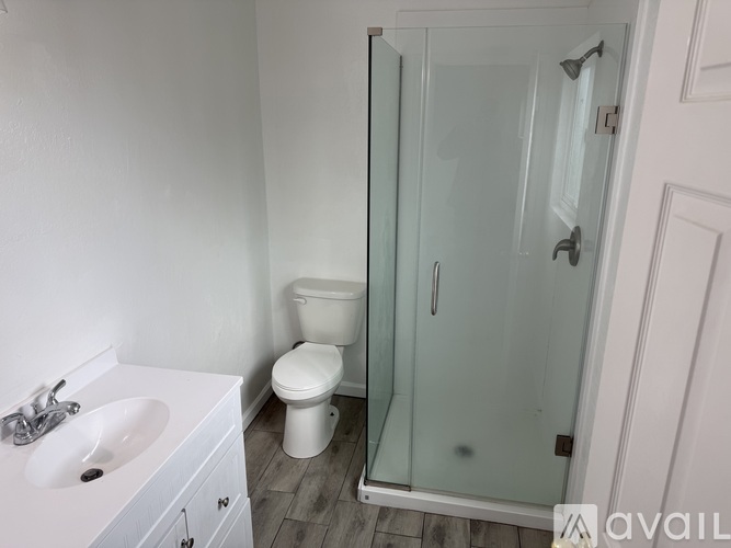 A white bathroom with a toilet, sink, and shower.