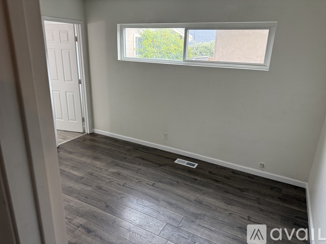 A room with a window and wooden flooring.