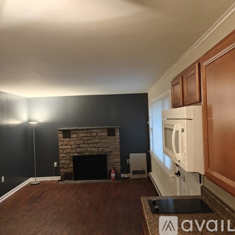 A living room with a stone fireplace and wooden cabinets.