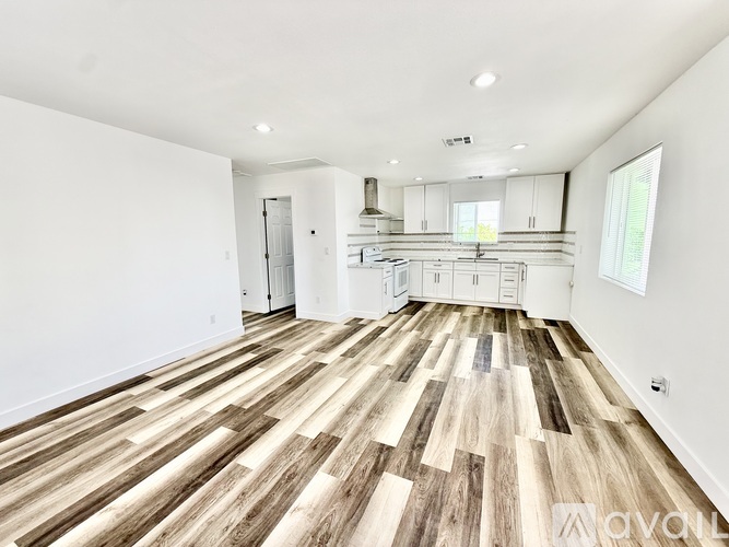 A spacious room with wooden flooring and white walls.