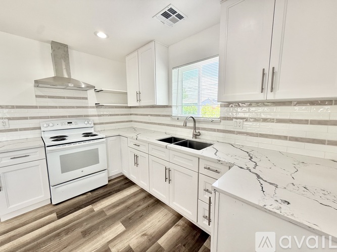 A kitchen with white cabinets and a marble countertop.