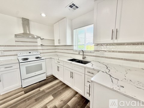 A kitchen with white cabinets and a marble countertop.