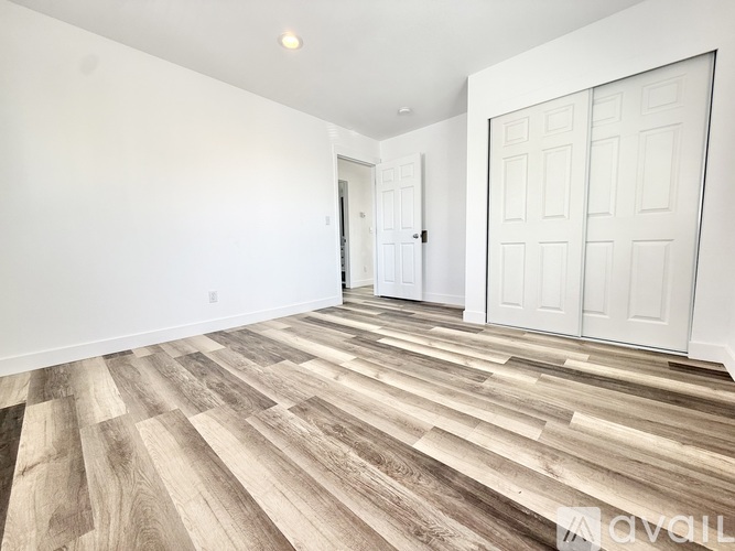A room with a white door and a wooden floor.