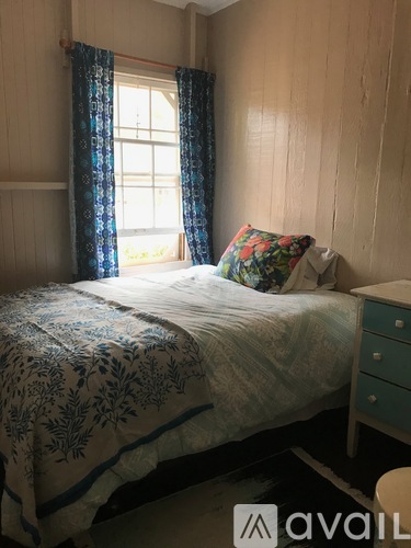 A bedroom with a bed, a window with curtains, and a pillow on the bed.