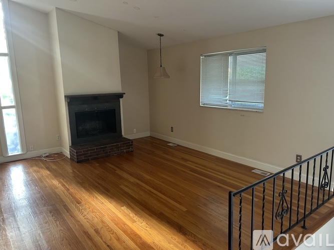 A living room with a fireplace and wooden floors.