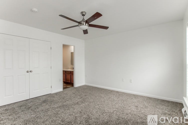 A room with a ceiling fan and carpeted floor.