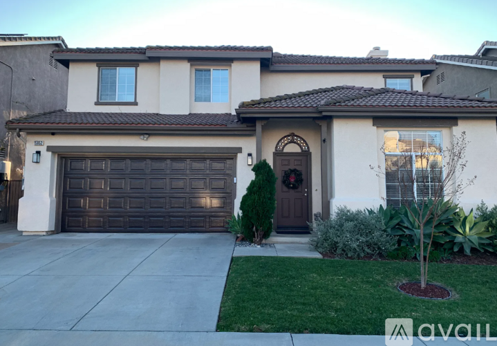 A house with a brown garage door and a brown door with a wreath on it.