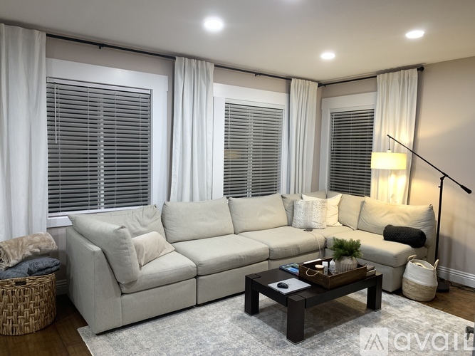 A living room with a white sofa, a coffee table, and a lamp.