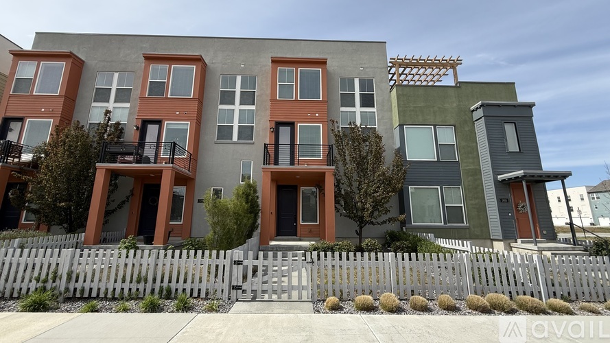A row of modern townhouses with a wooden fence in front.