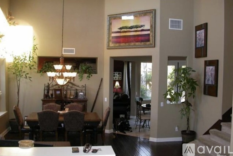 A dining room with a table set for two and a painting hanging on the wall.